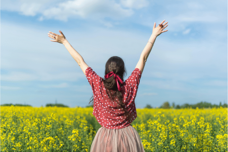 Young adult embracing the sunlight with arms wide in a field of yellow blooms, symbolizing a heart devoted to living for God.